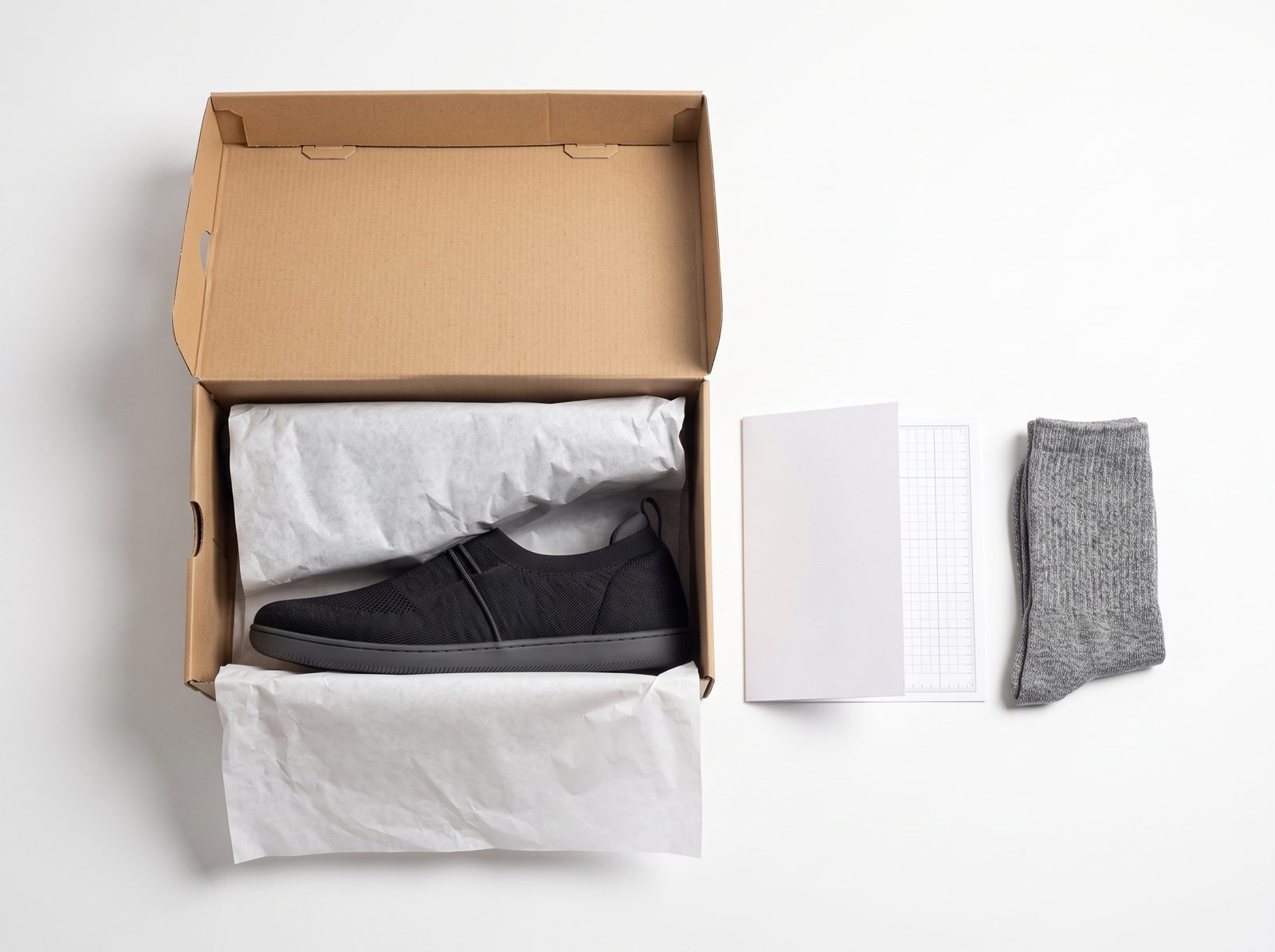 Open Ample shoe box with a shoe, a folded card, a blank foot-measure sheet and a pair of socks